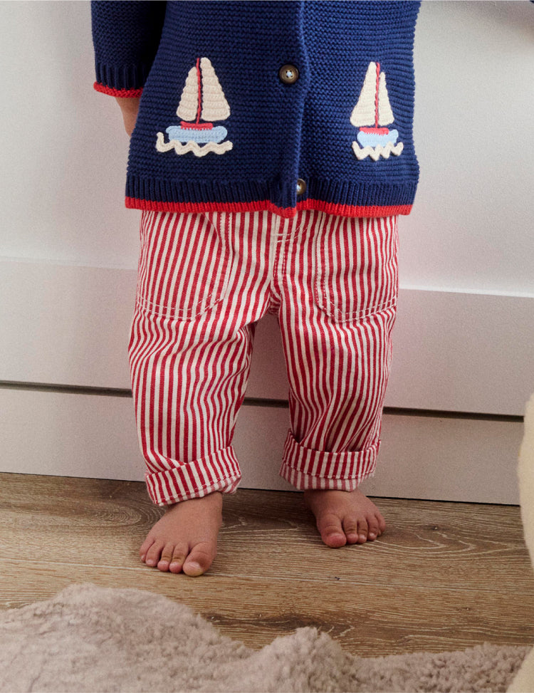 Photo of a baby from the shoulders down wearing knit cardigan and striped pants from Boden