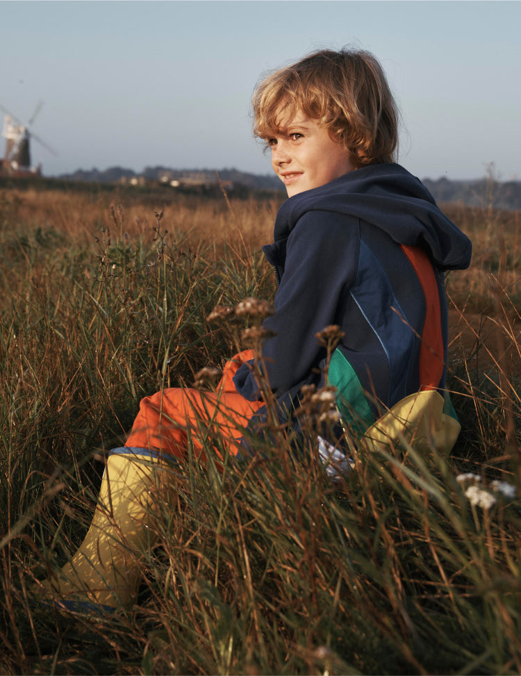 Boy sat in a field wearing a Boden hoodie.