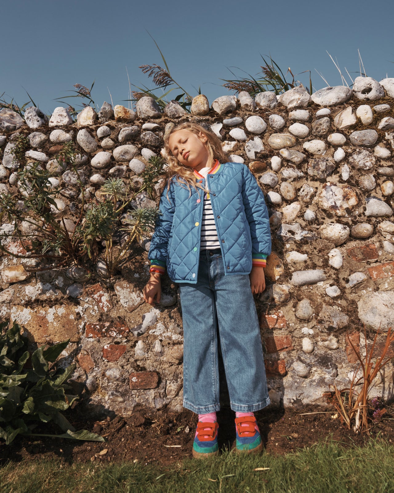 Girl leaning against a stone wall wearing a full Boden outfit