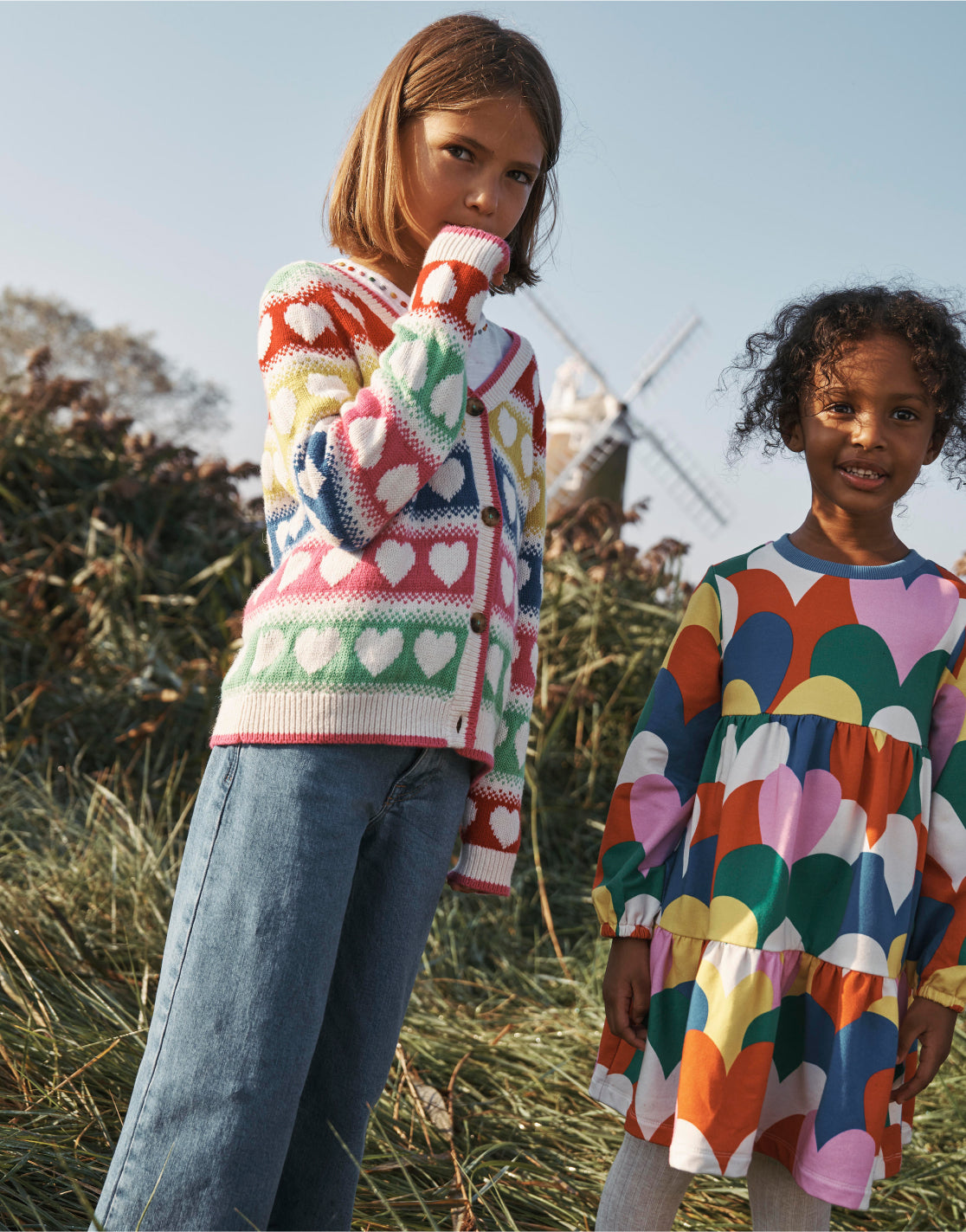 Two girls standing in a field wearing Boden heart print clothing.