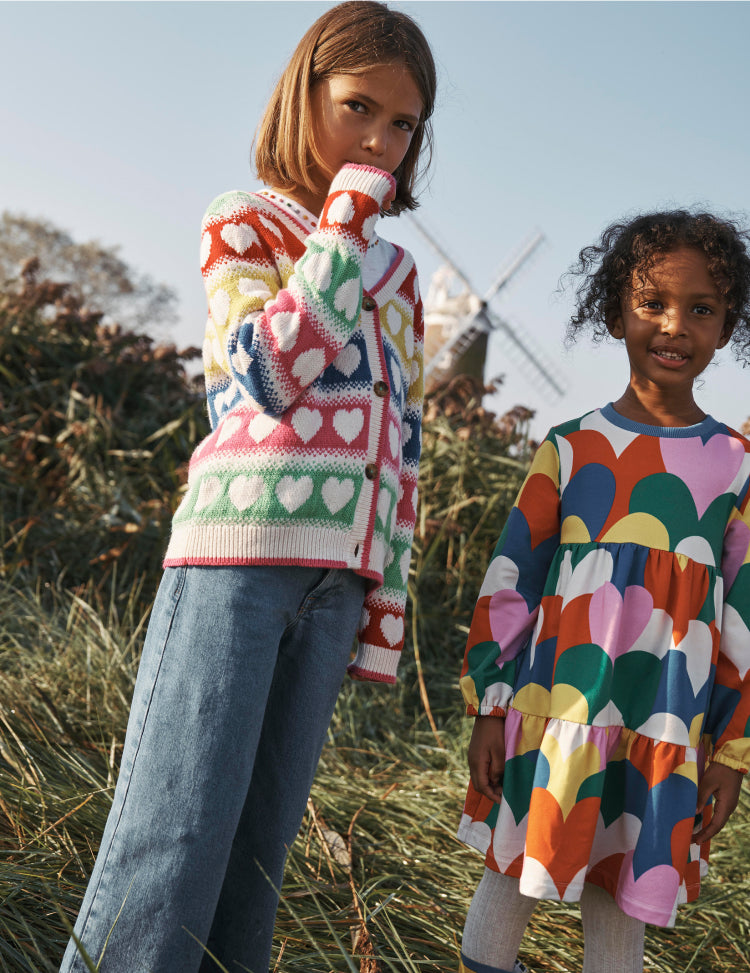 Two girls standing in a field wearing Boden heart print clothing.