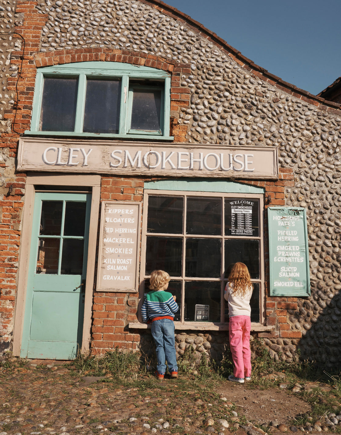 A boy and a girl looking into a shop window, both wering Boden sweaters