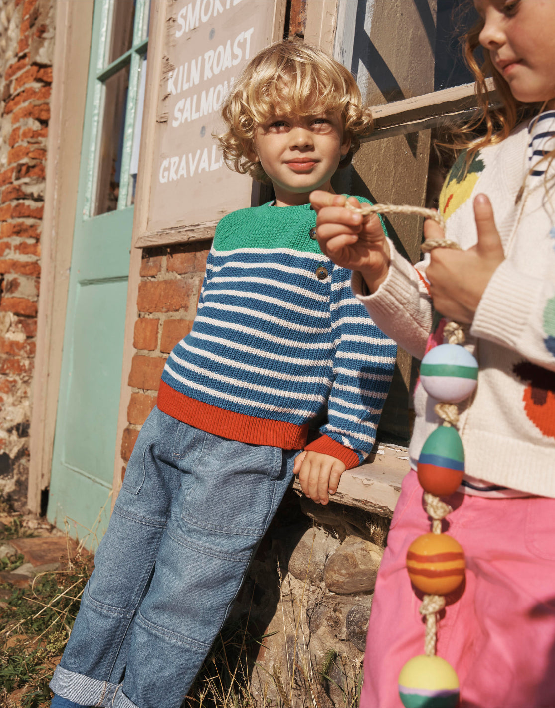 Boy and girl leaning against a shop window wearing Boden knits.