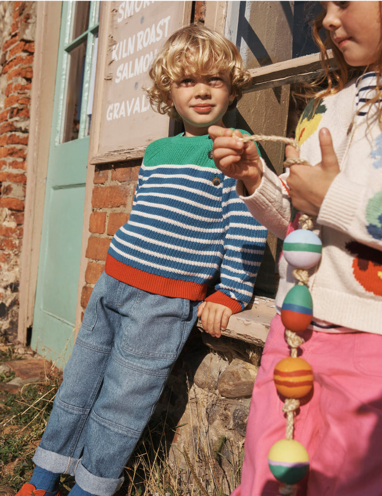 Boy and girl leaning against a shop window wearing Boden knits.