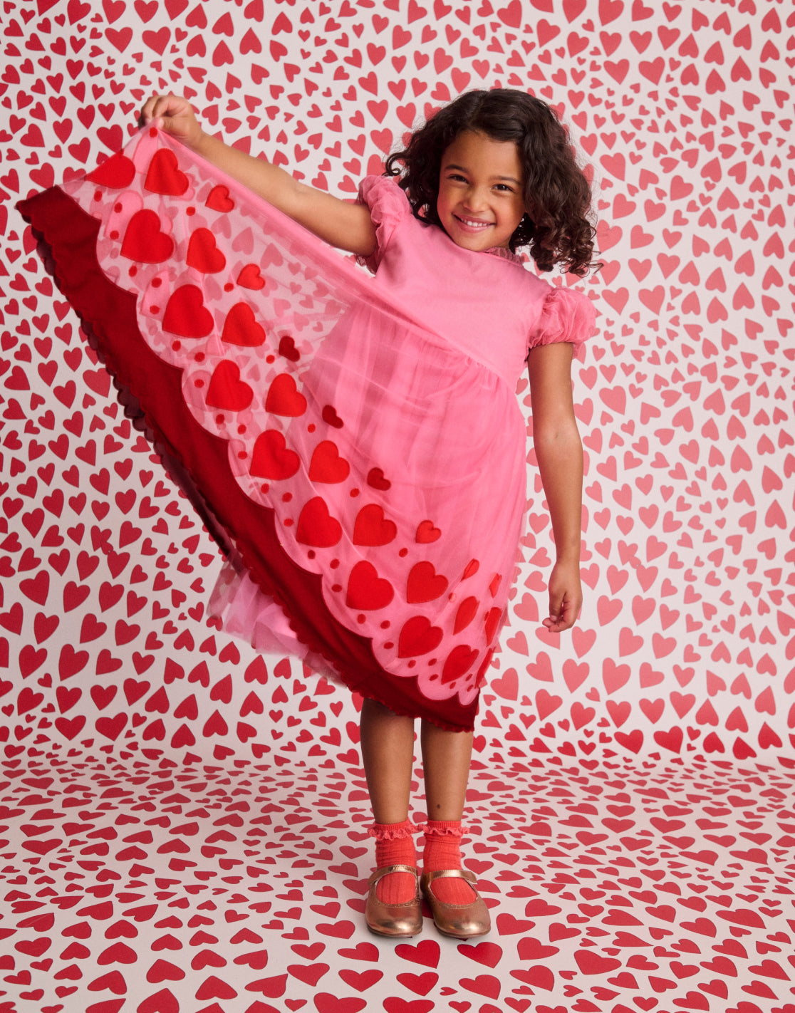 Girl wearing a Boden dress with Pink Hearts